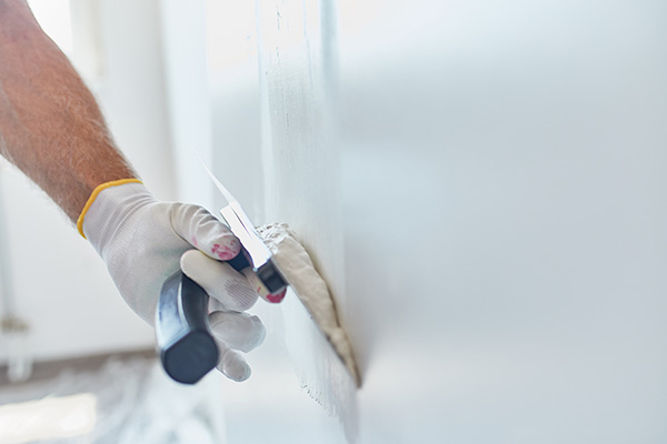 hand applying plaster to a wall with a trowel indicating a home improvement project involving eight wall sections