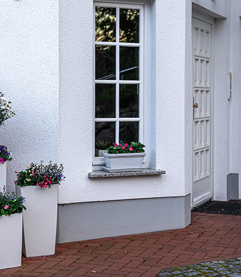 white house exterior with window potted flowers and door showcasing 5 vibrant flower arrangements